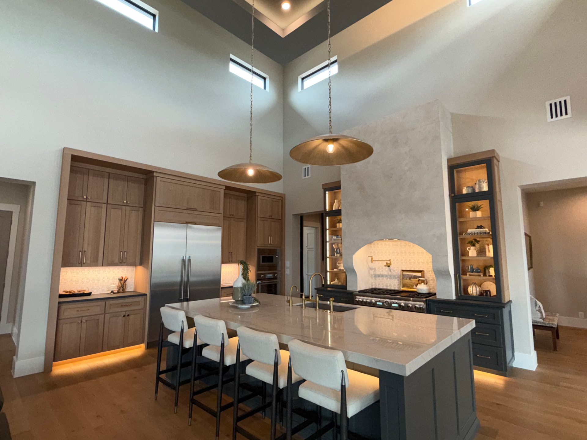 Vaulted custom kitchen with brass dome pendants and a marble island by Amaya Custom Cabinets in San Antonio
