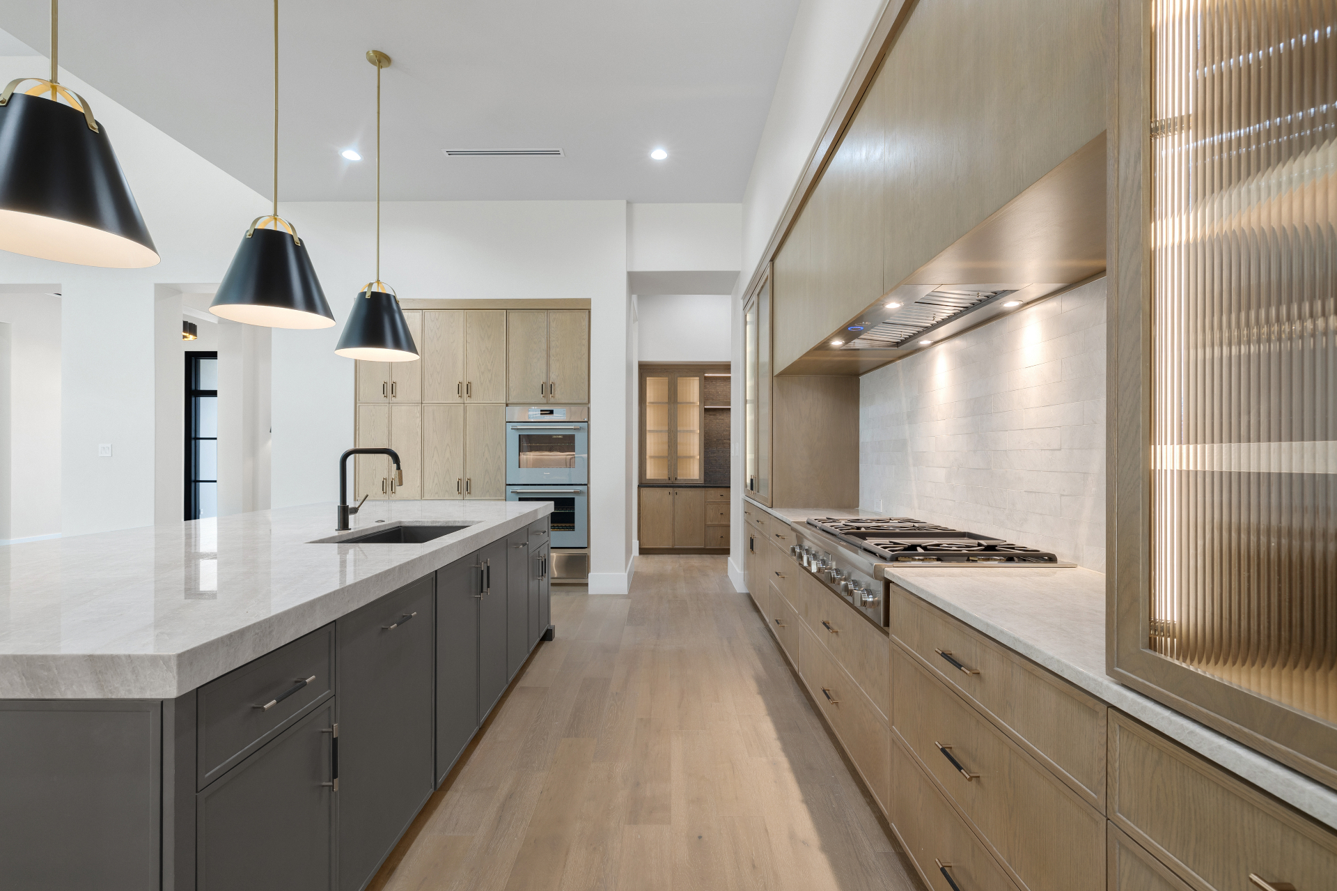 Galley view with range wall and reeded glass cabinets in The Dominion kitchen by Amaya