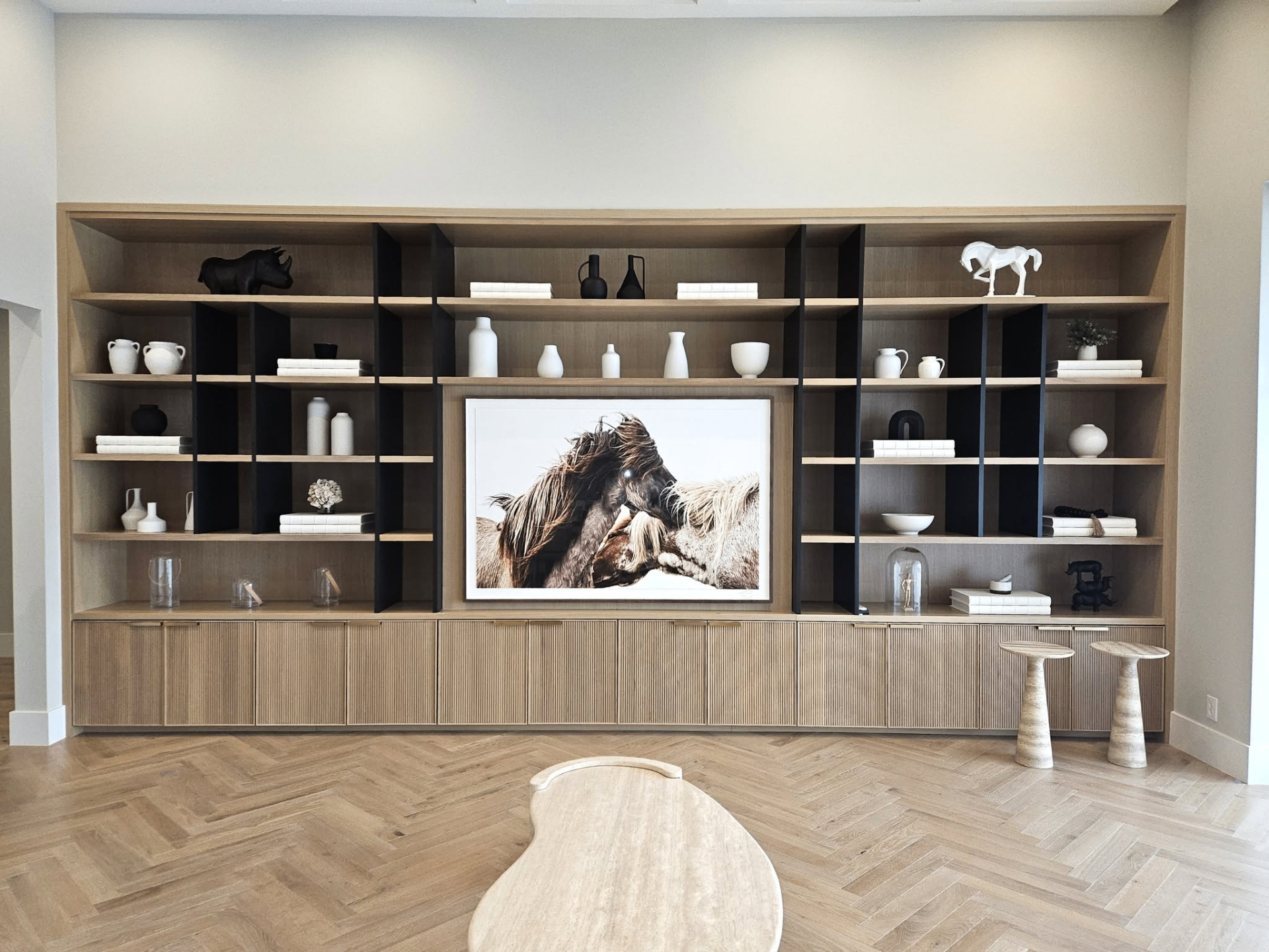Floor-to-ceiling white oak shelving with reeded base cabinetry by Amaya