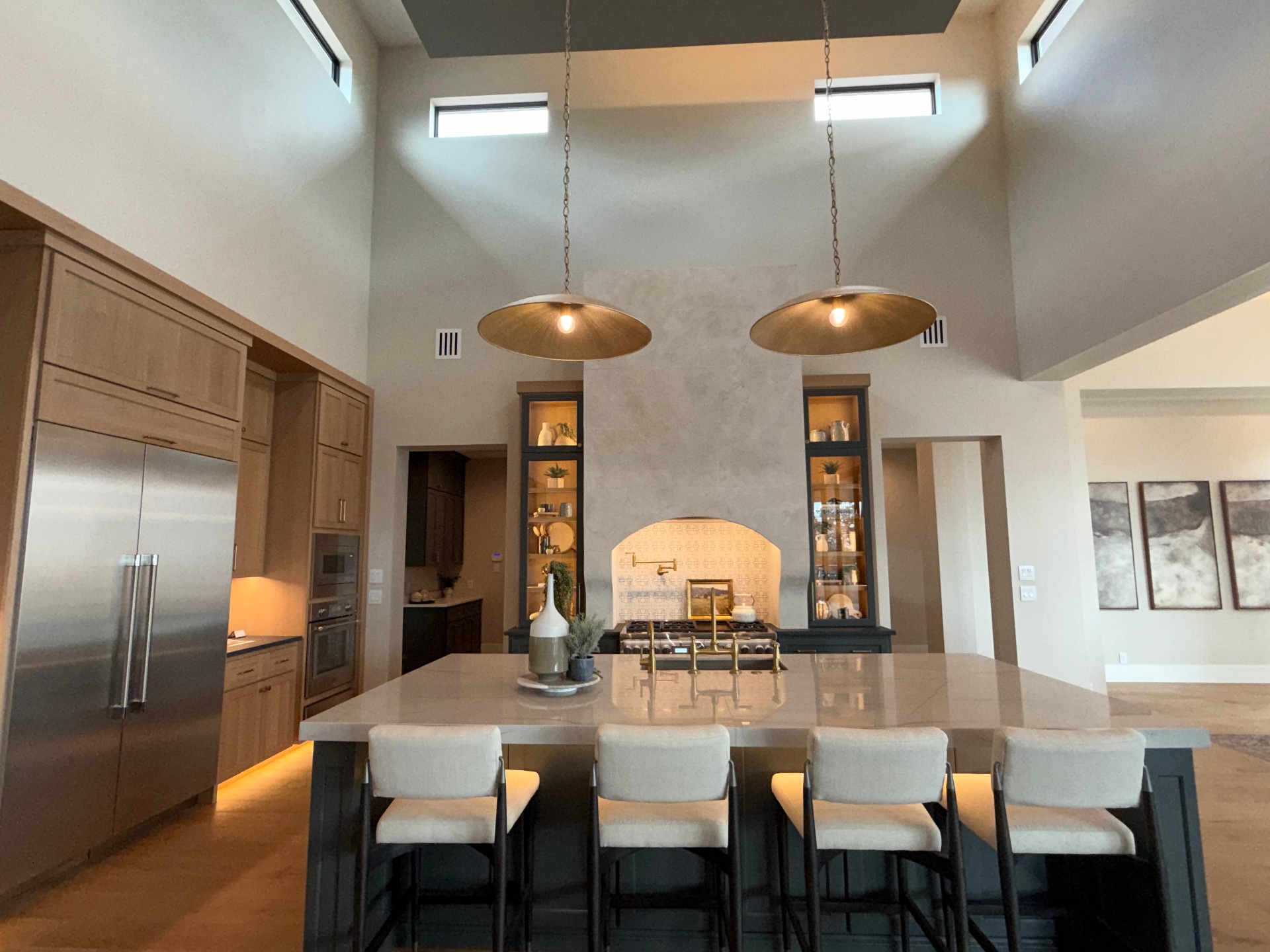 Plaster hearth range wall flanked by graphite display towers with integrated lighting by Amaya