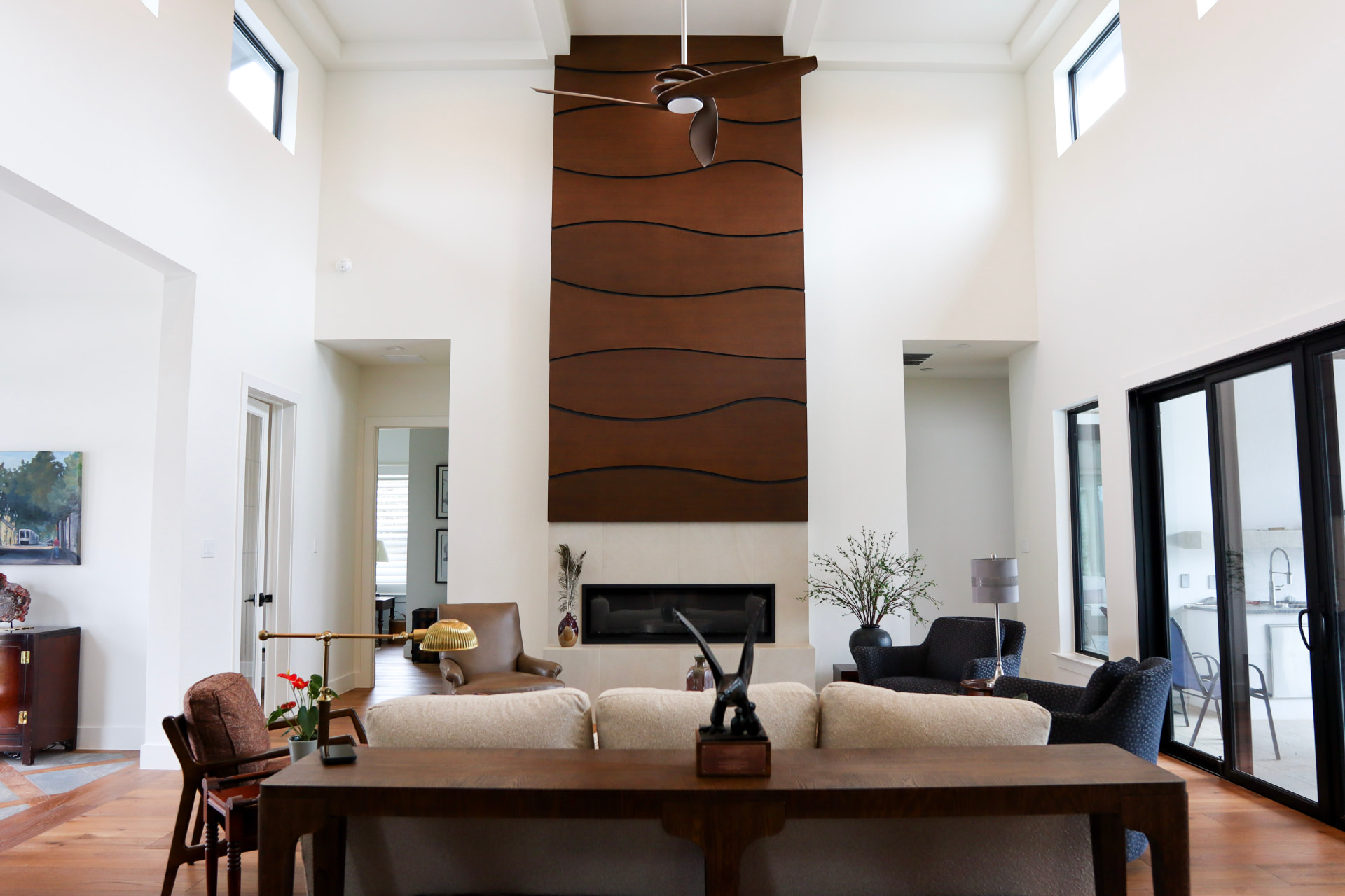 Two-story rift-sawn white oak fireplace surround with sculpted wave-panel millwork by Amaya Custom Cabinets in San Antonio.